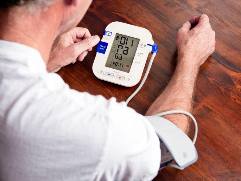 Man using blood pressure monitor. (cglade, iStockphoto)