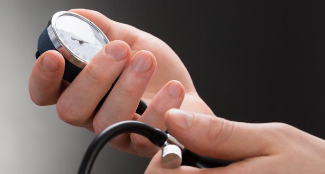 Hands holding blood pressure monitor